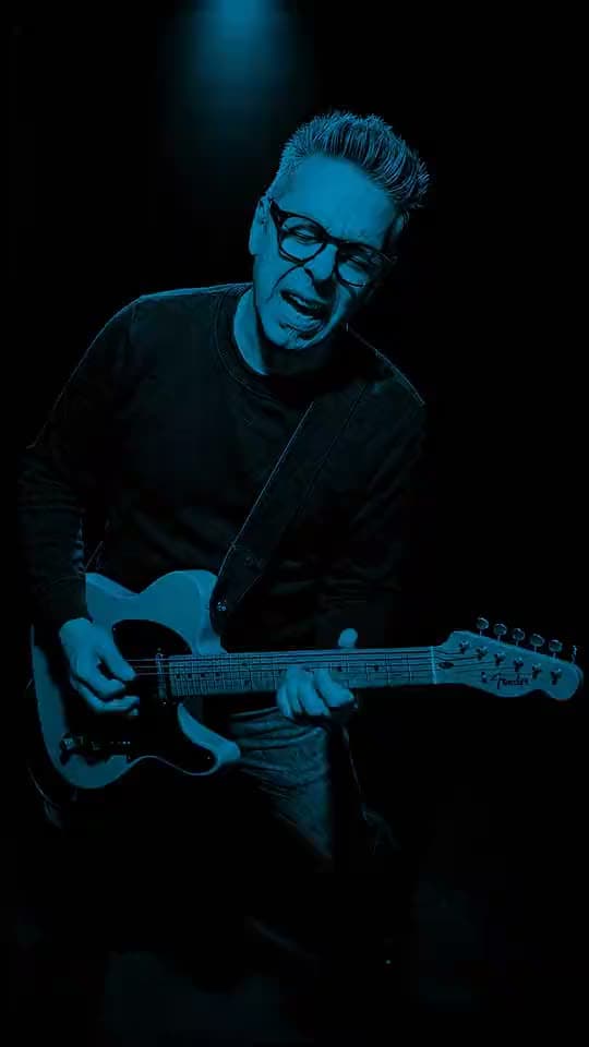The BluesMaker performing Call Me Analog Man, rim-lit on a dark stage.