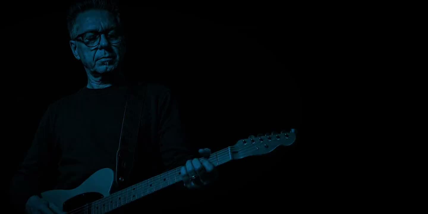 The BluesMaker performing Call Me Analog Man, rim-lit on a dark stage.
